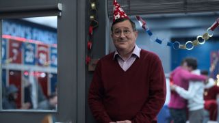 Higgins standing in Ted's office wearing a Christmas hat.