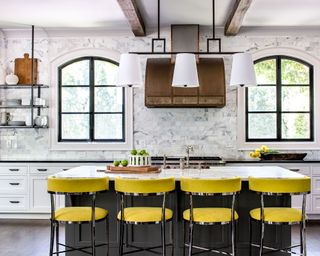 Large kitchen with marble tiled wall and island with yellow stools
