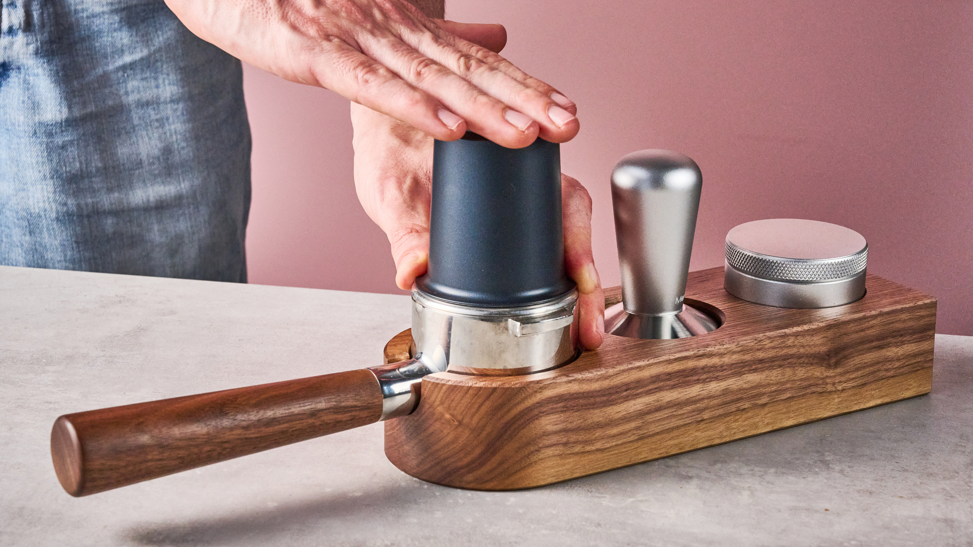 A man taps on top of the Meraki Espresso Machine's dosing cup, transferring the grounds into the portafilter.