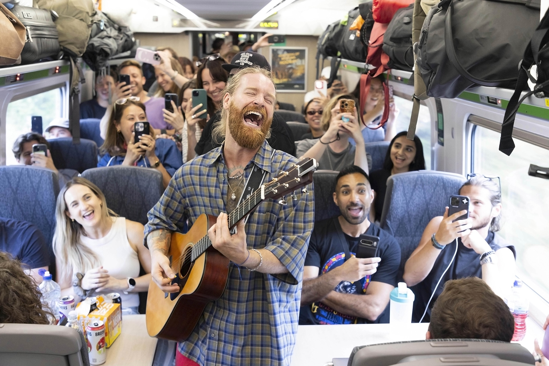 Photo of musician Sam Ryder performing an impromptu gig onboard a train service traveling from Paddington Station to Glastonbury, UK.
