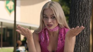 Margot Robbie's Barbie looking distressed with her hands up in a questioning gesture.