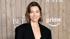 Jessica Biel standing in front of wooden board with signage of Better Sister television show