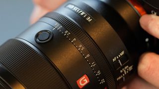 The lens features a physical aperture ring and two focus hold buttons, one of which is seen here on the left-hand side. Image Credit: TechRadar