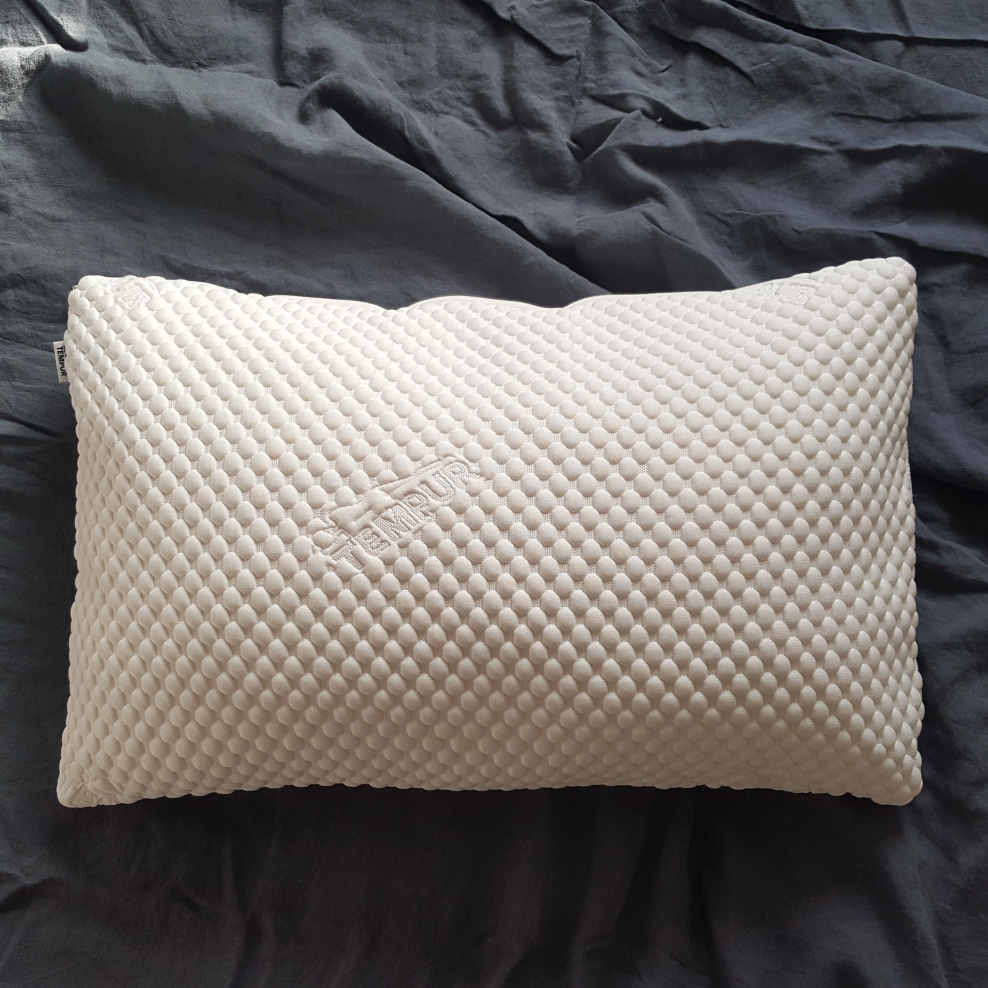 The Tempur Comfort Cloud pillow being tested on a bed with grey bedlinen