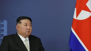 north korean leader kim jong un sits beside the nation's flag
