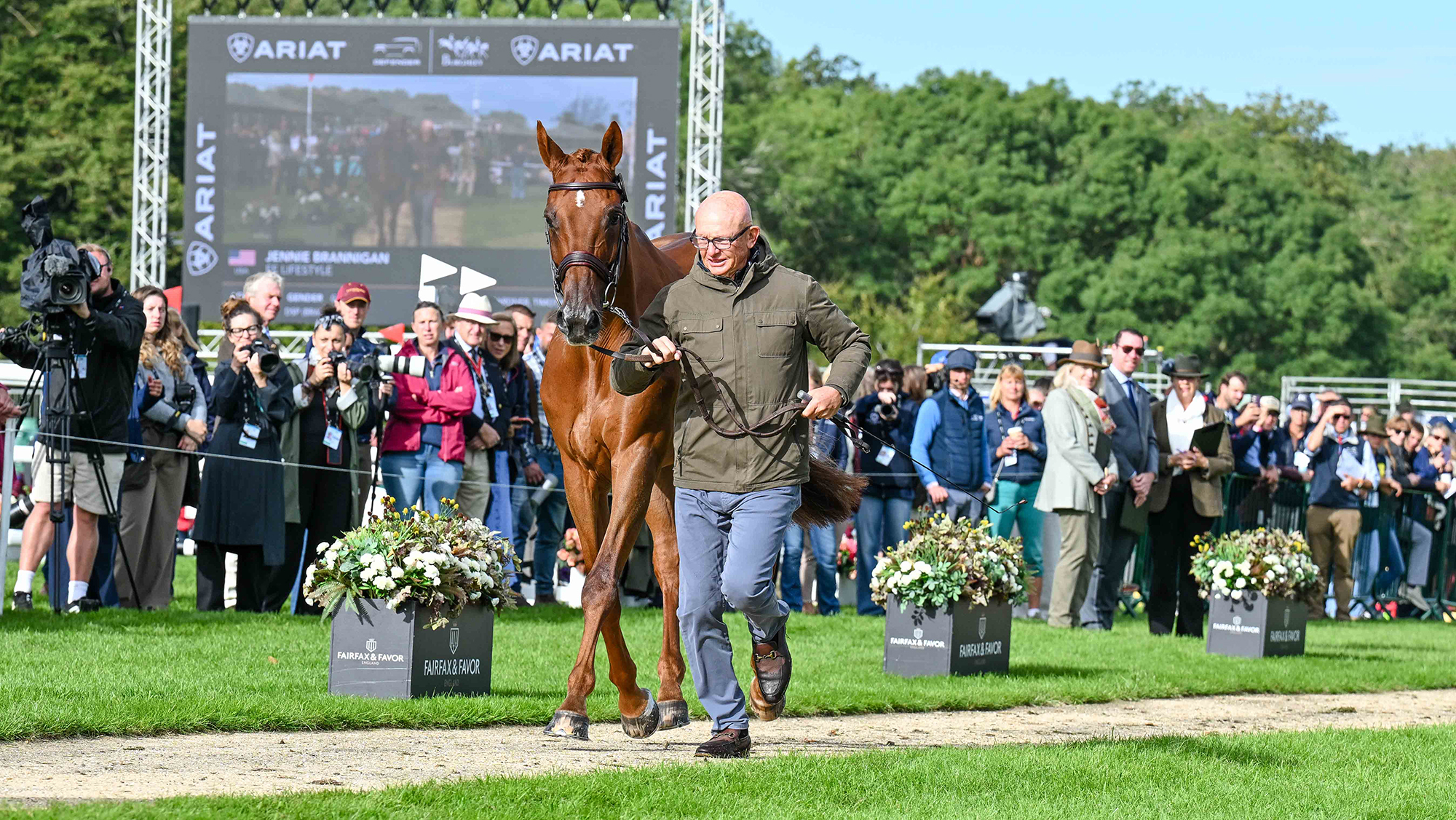 Leslie Law, a bald man in a green coat, trots up chestnut horse FE Lifestyle at Burghley 2026