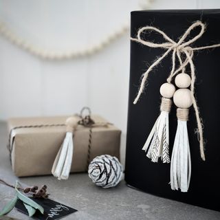 Wooden bead tassels on black and Kraft paper wrapped gifts with pinecones