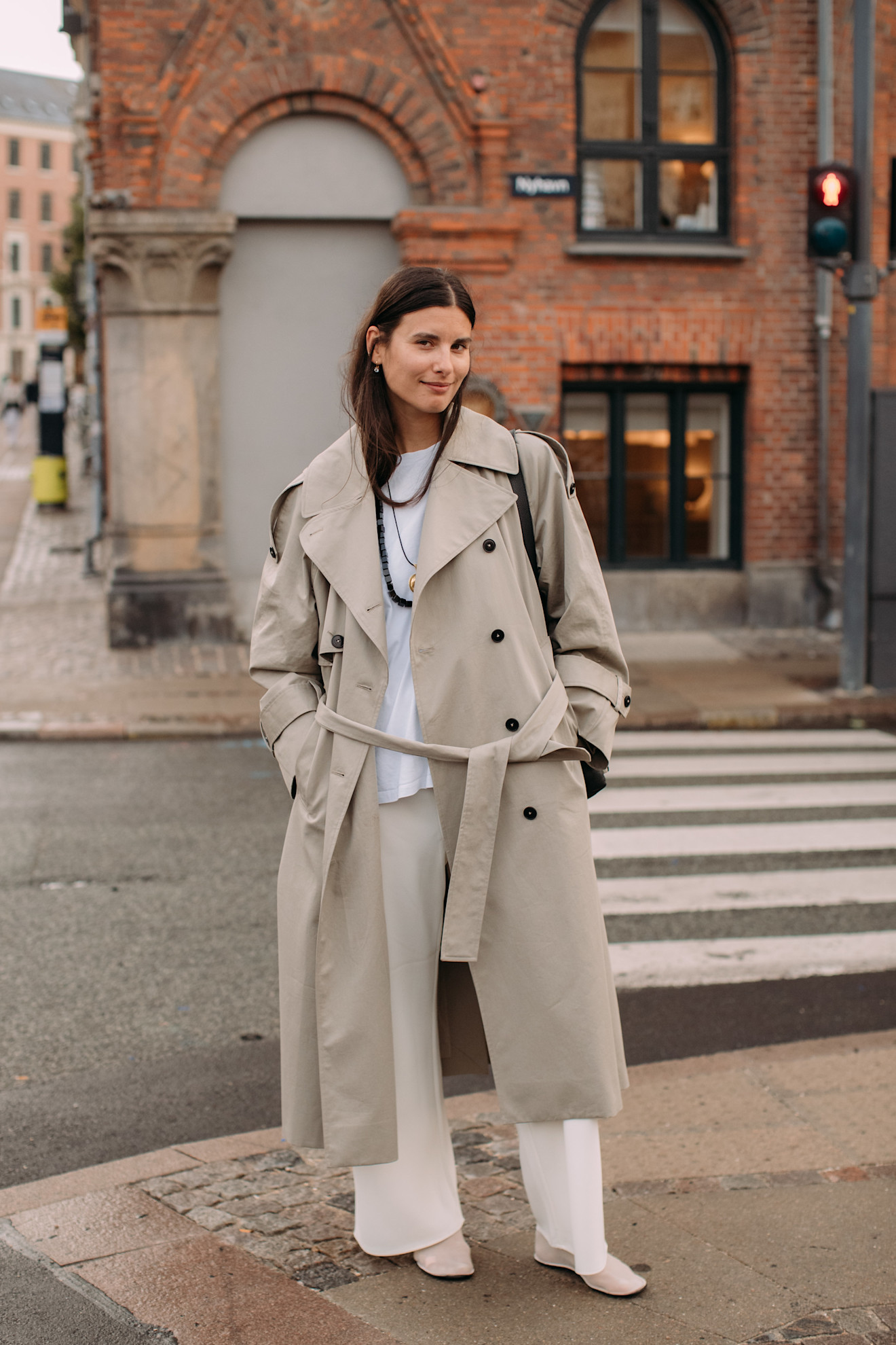 fashion week attendee wears trench coat and white pants