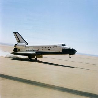 The rear wheels of the space shuttle orbiter Columbia touch down on Rogers dry lake at Edwards Air Force Base in southern California to successfully complete a stay in space of more than two days on April 14, 1981. The mission marked the first NASA flight