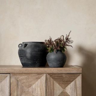 A black ceramic vase on a wooden console table