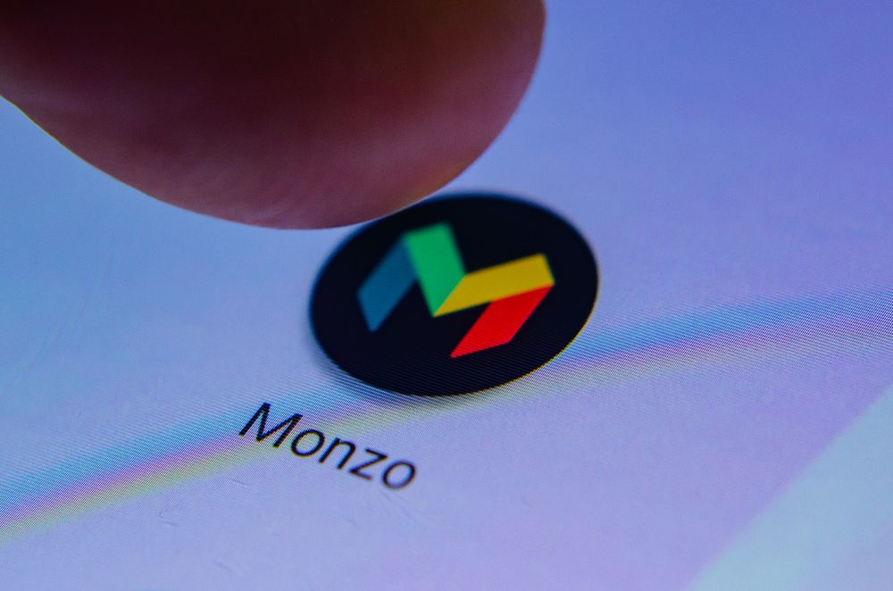 A finger pressing Monzo&amp;#039;s App icon on a phone 