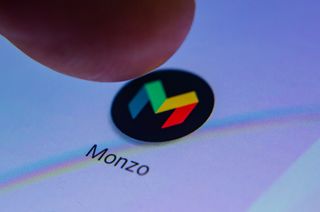 A finger pressing Monzo's App icon on a phone 