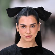 a woman with black hair wearing a large black hair bow