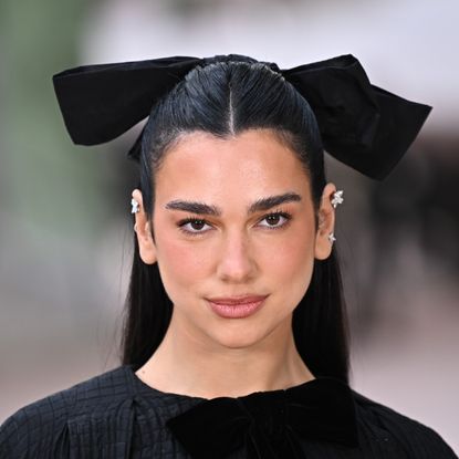 a woman with black hair wearing a large black hair bow