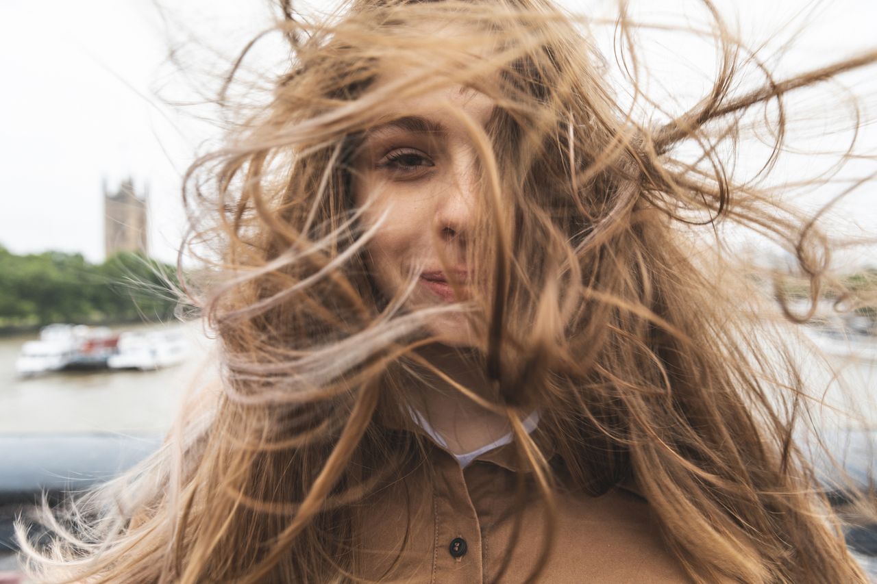 Portrait of smiling young woman with windswept hair, London, UK