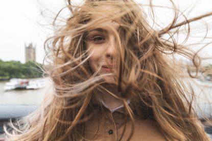 Portrait of smiling young woman with windswept hair, London, UK