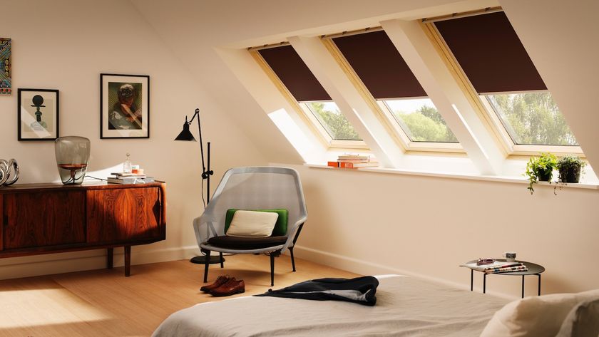 Loft conversion with a bed, sideboard and armchair, and three pitched windows with blinds