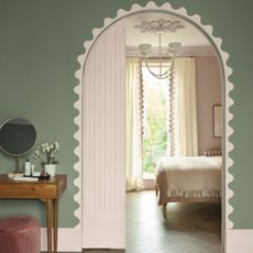 An arched doorway leading into a pink bedroom with a wavy border painted around the arch