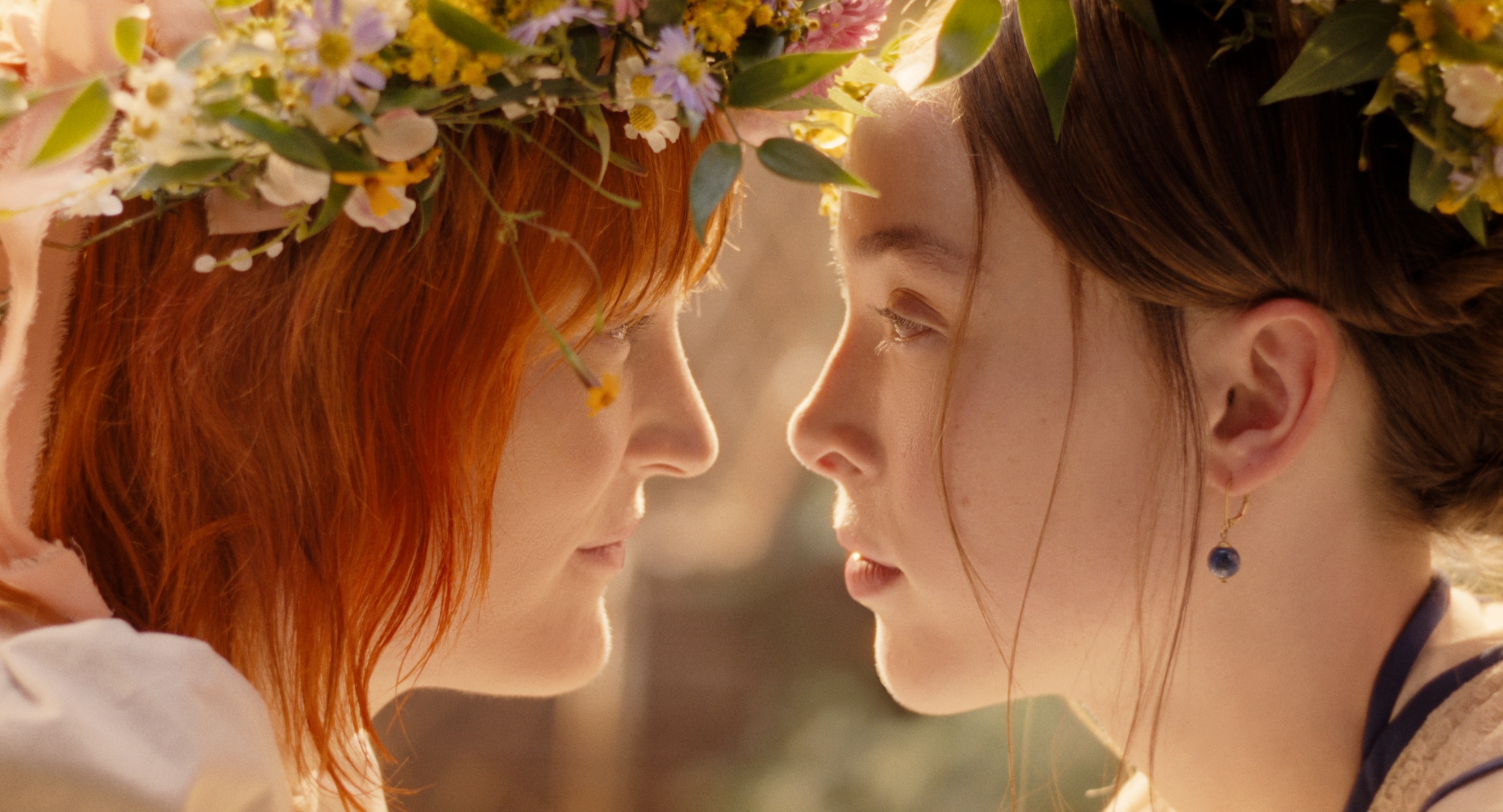 vicky krieps as bridget sullivan wearing a flower crown and leaning in closely to stare into ella beatty as lizzie borden's eyes in a still from monster the lizzie borden story