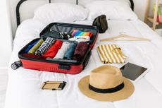 An open suitcase with a hat, device, socks, and other travel essentials