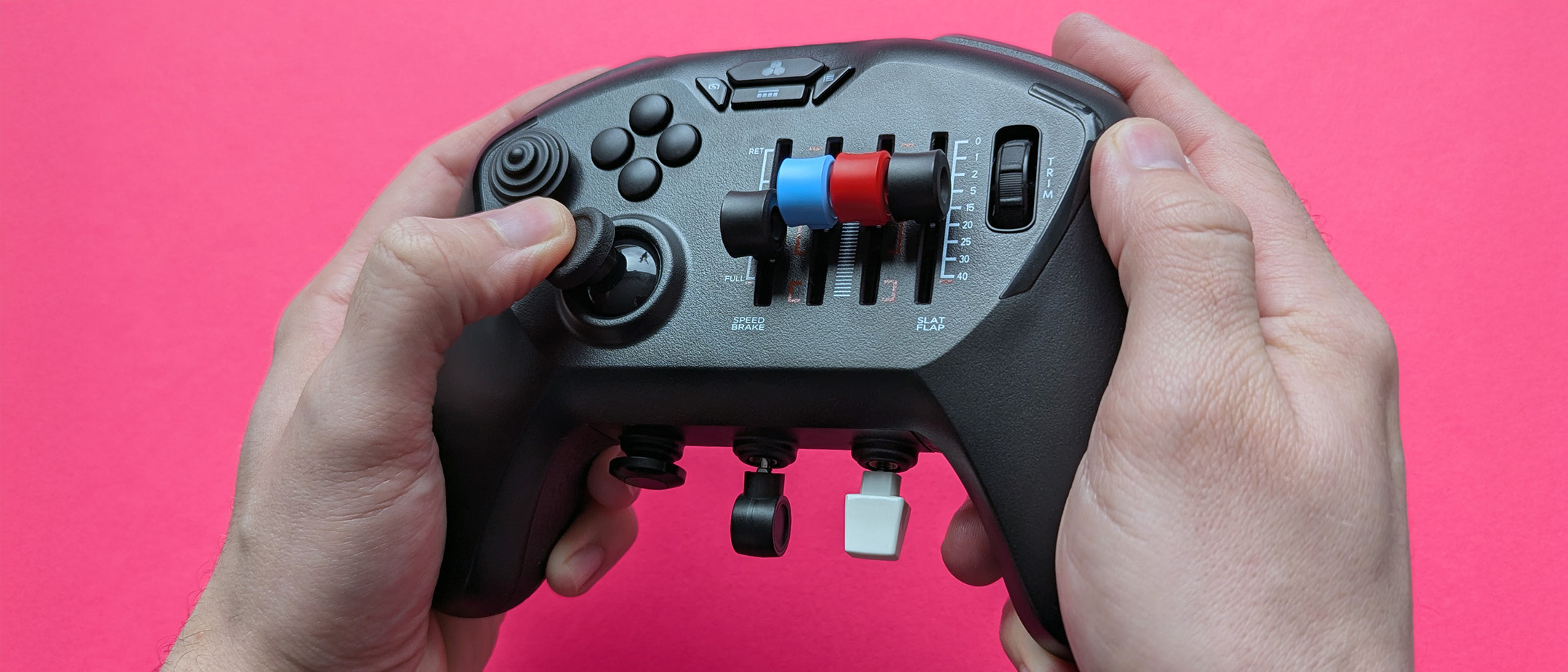 Honeycomb Aeronautical Echo Aviation Controller held in two hands with a magenta cardstock background