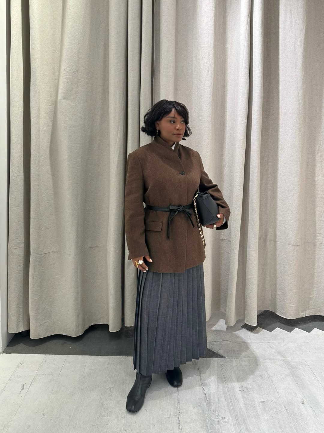 Franny Mozemba wearing a brown blazer with gray pleated skirt.