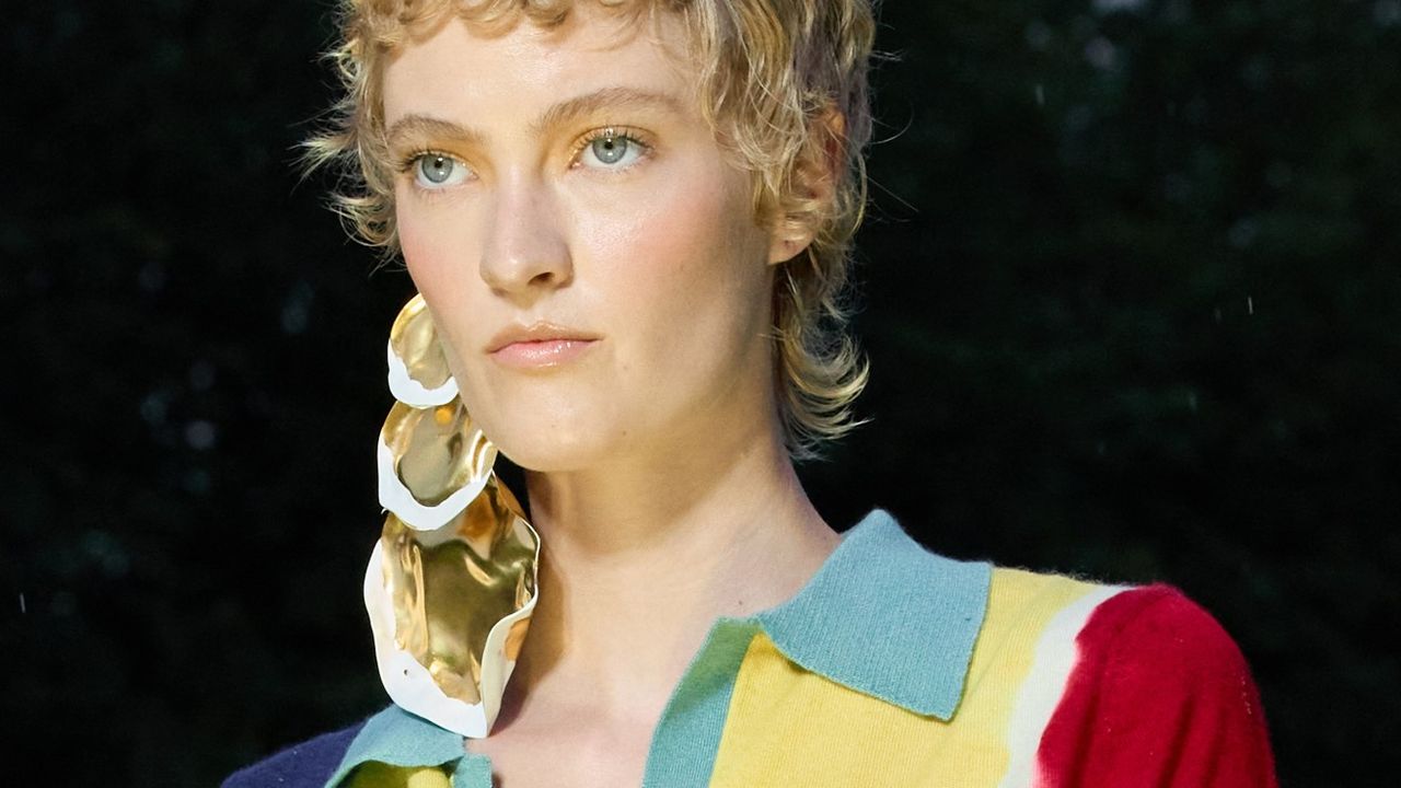 A model with a curly short wolf cut walking the runway.