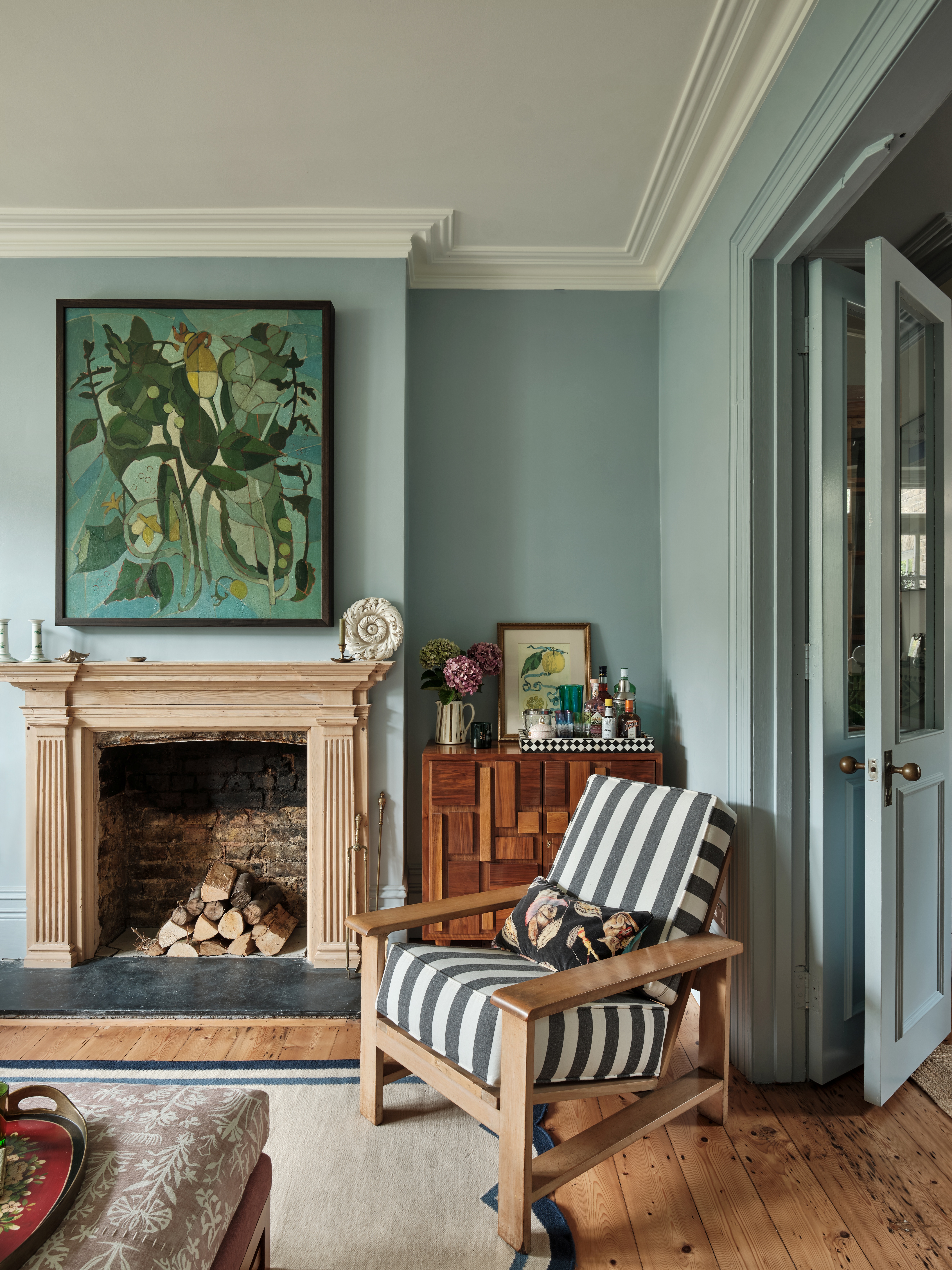 Interiors of a country-chic home with wooden floors, beige, pale blue, and rose pink walls, curated colorful artwork, and soft forms.