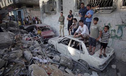 Palestinians look over destroyed home