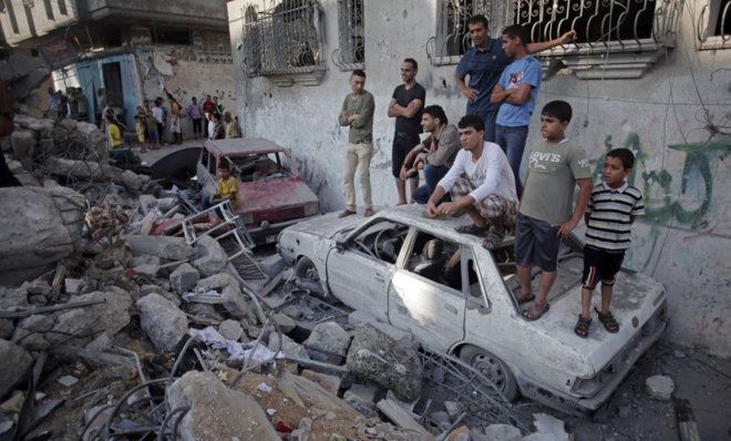 Palestinians look over destroyed home