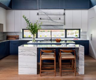 White kitchen with marble island and wooden bar stools