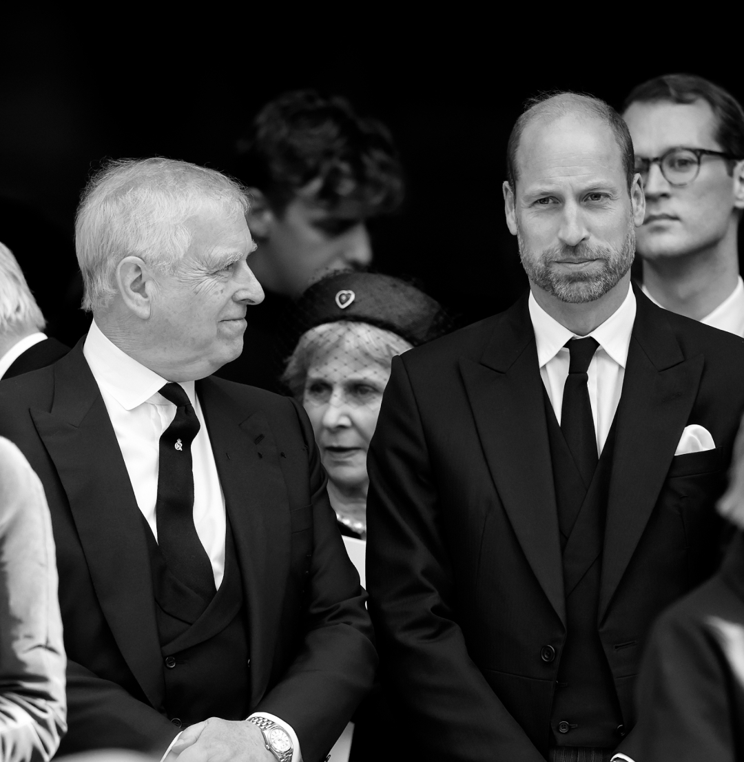 Prince William, wearing a black suit at Duchess of Kent's funeral, looking serious as Prince Andrew turns to smile at him