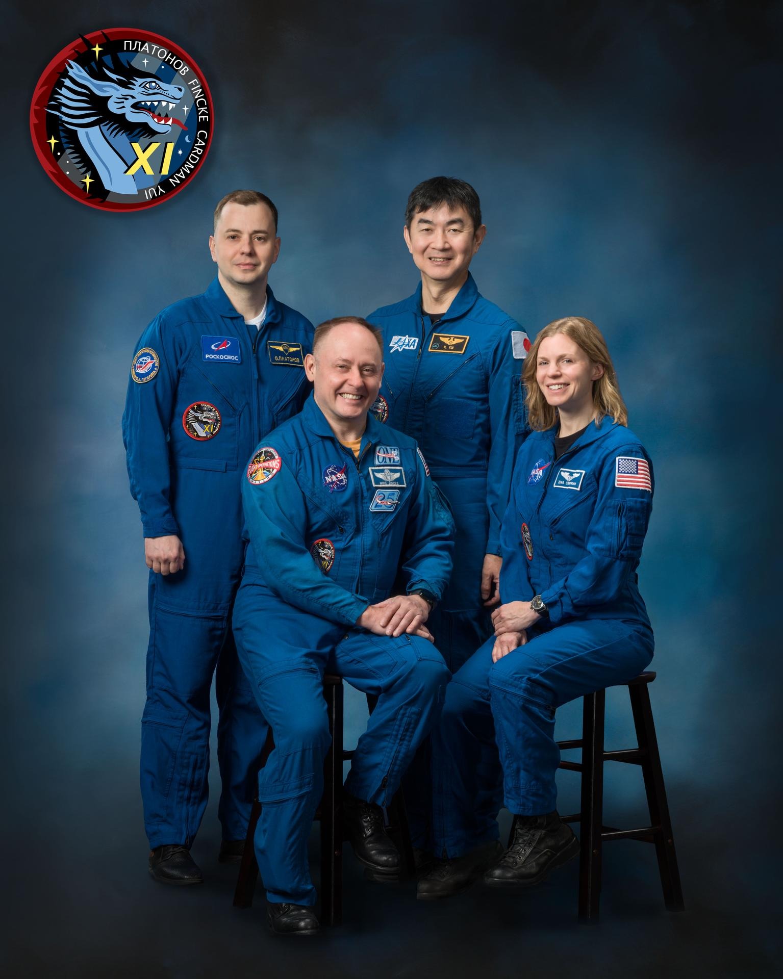four people in blue flight suits smile and pose for a portrait