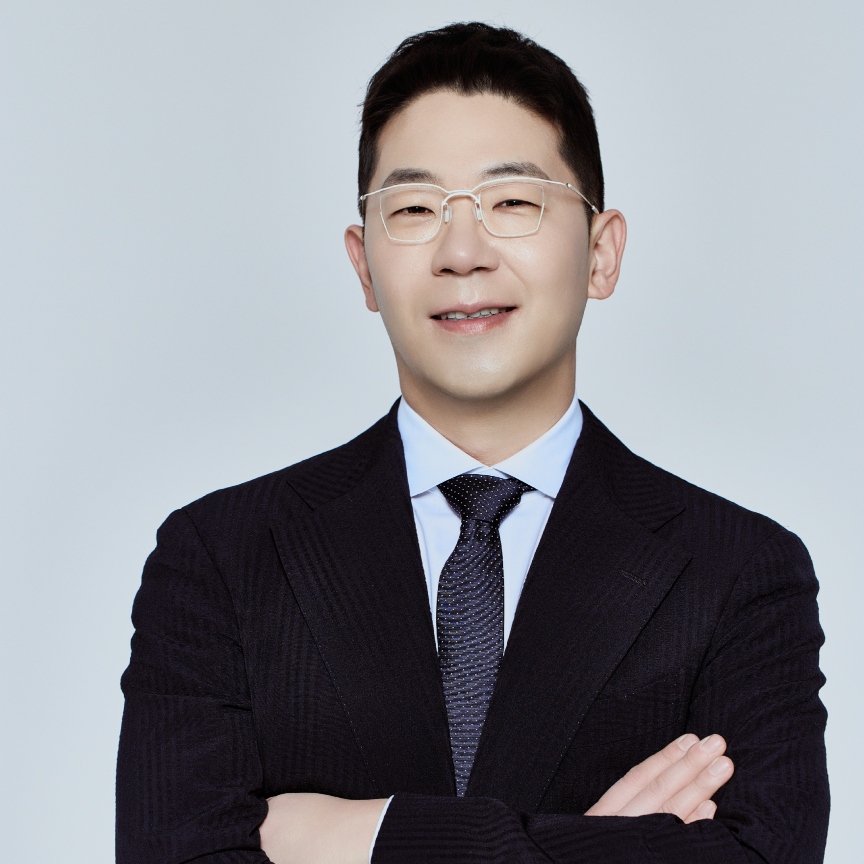 a young asian man in a black suit and white shirt with glasses