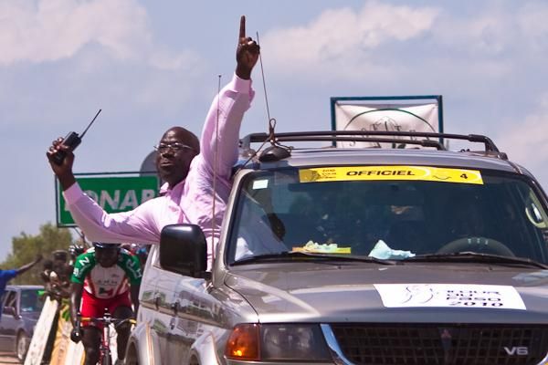 The president of the Burkina Faso Cycling Federation celebrates as he crosses the line behind his victorious riders.