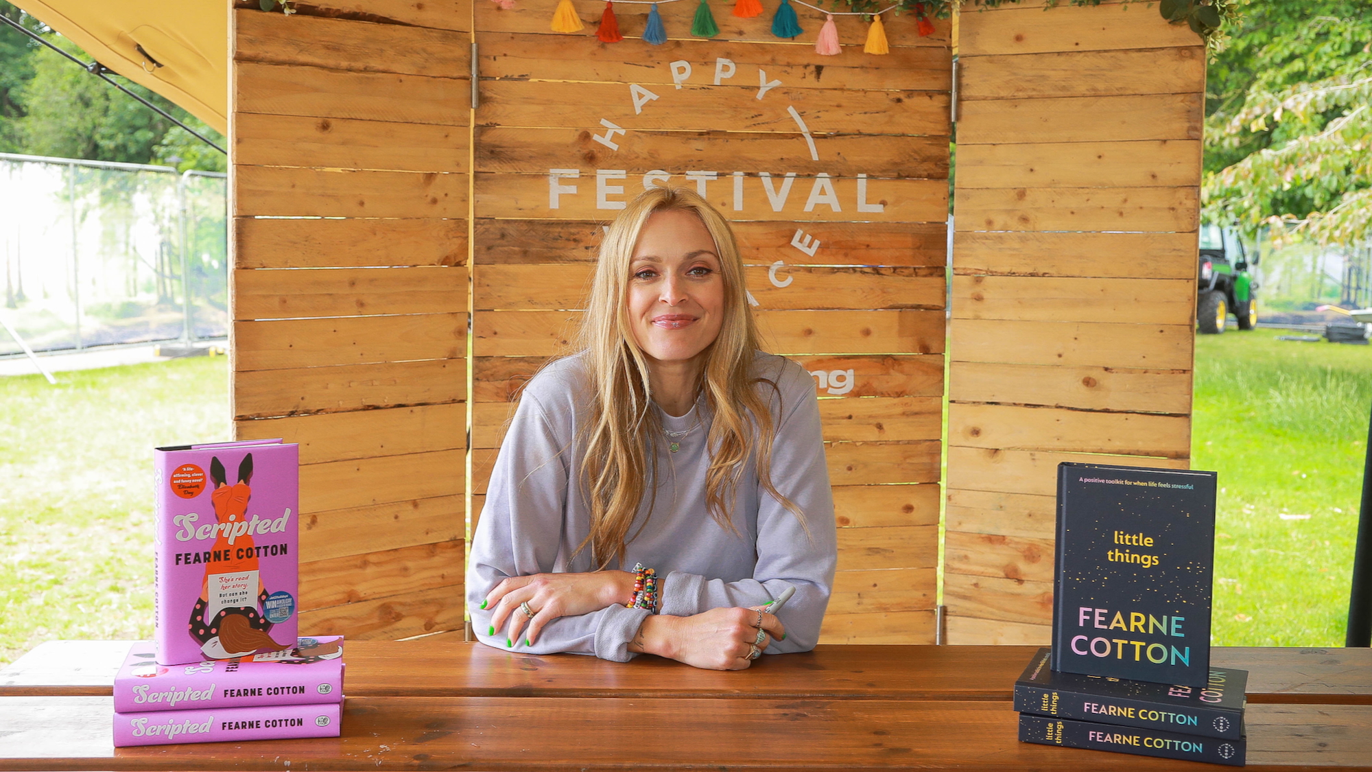 Fearne Cotton sits at a wooden table with her books Scripted and Little Things, at Fearne Cotton's 2024 Happy Place Festival