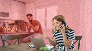 Young woman sitting at a kitchen table in front of a laptop, and talking on the phone
