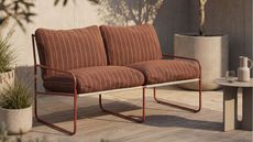 Cult Furniture's Harris Garden Sofa in rust red on a modern patio with neutral-toned flooring, side table and plant pots