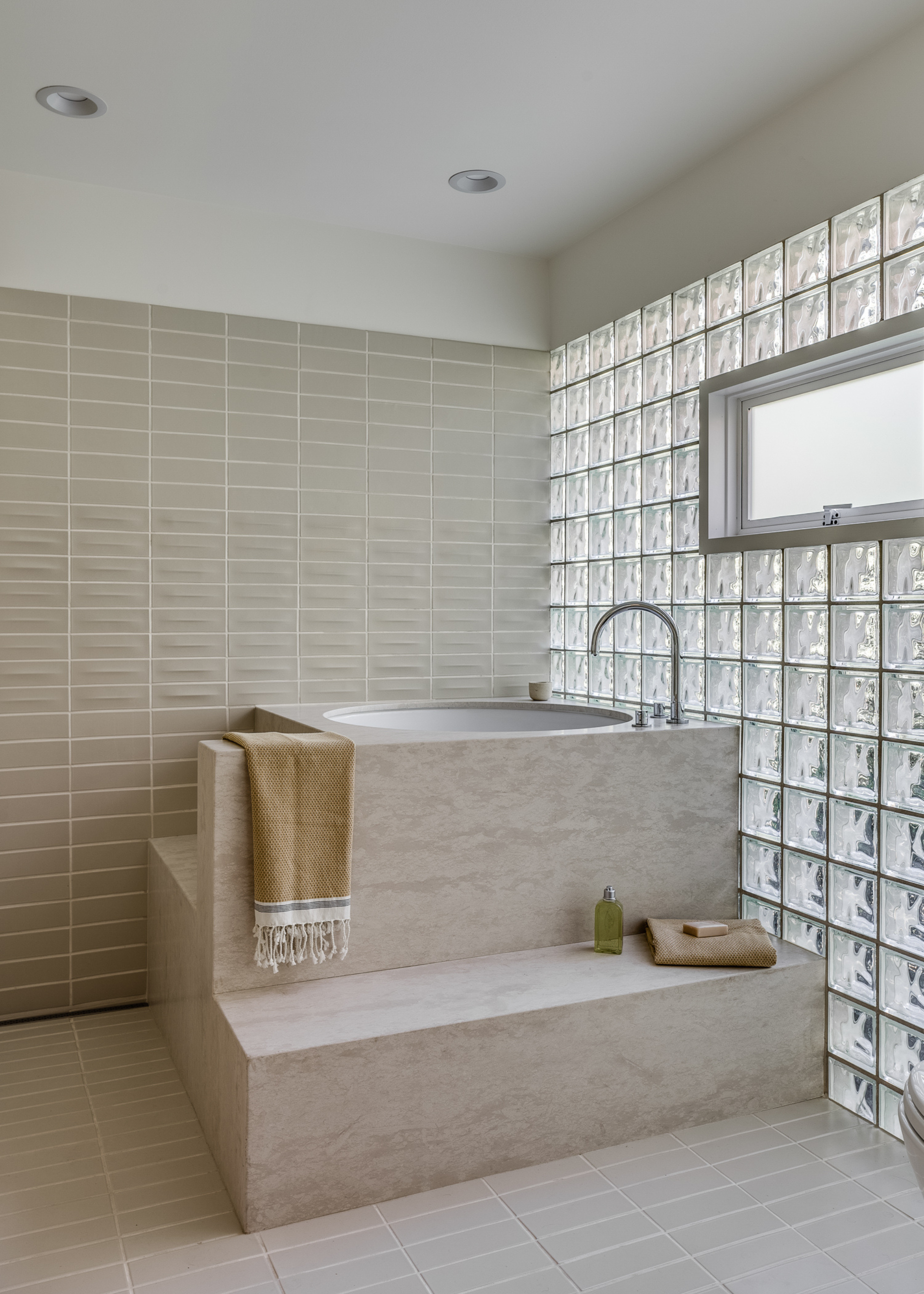 a neutral toned bathroom with a full glass block wall