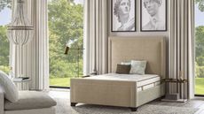 The Saatva Latex Hybrid Mattress on a bed beneath classical paintings against windows with a garden view.