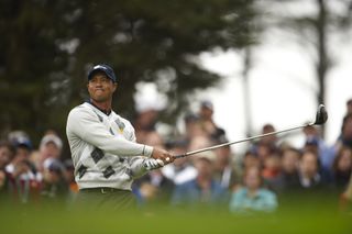 Tiger Woods strikes a tee shot with a driver