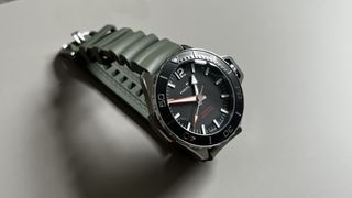 The Hamilton Khaki Navy Frogman with a black dial and a green rubber strap on a grey background