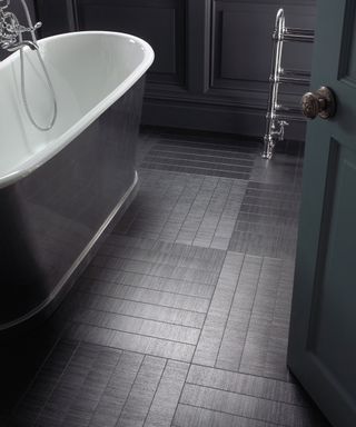 Black vinyl flooring in bathroom with white and grey bath, black painted walls