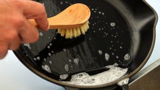 Scrubbing a cast iron skillet with soapy water