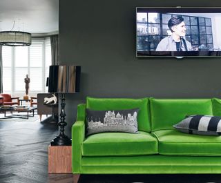 media room ideas with green sofa and TV on a black wall