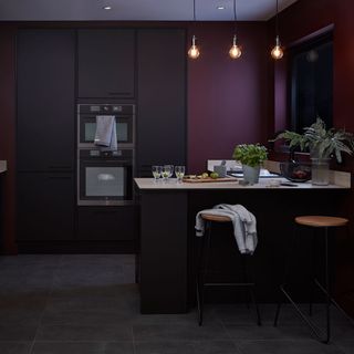 kitchen with dark black wall and oak wood table with hanging lights