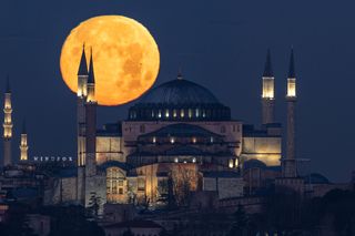 the full moon behind a large mosque, with spires