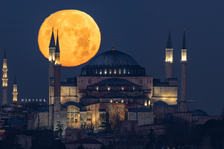 Full moon behind a large mosque, with towers