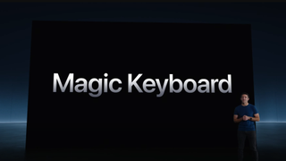 A man standing on a stage with the backdrop announcing the Magic Keyboard in text