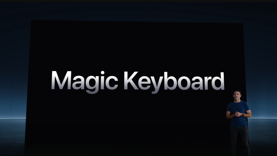 A man standing on a stage with the backdrop announcing the Magic Keyboard in text